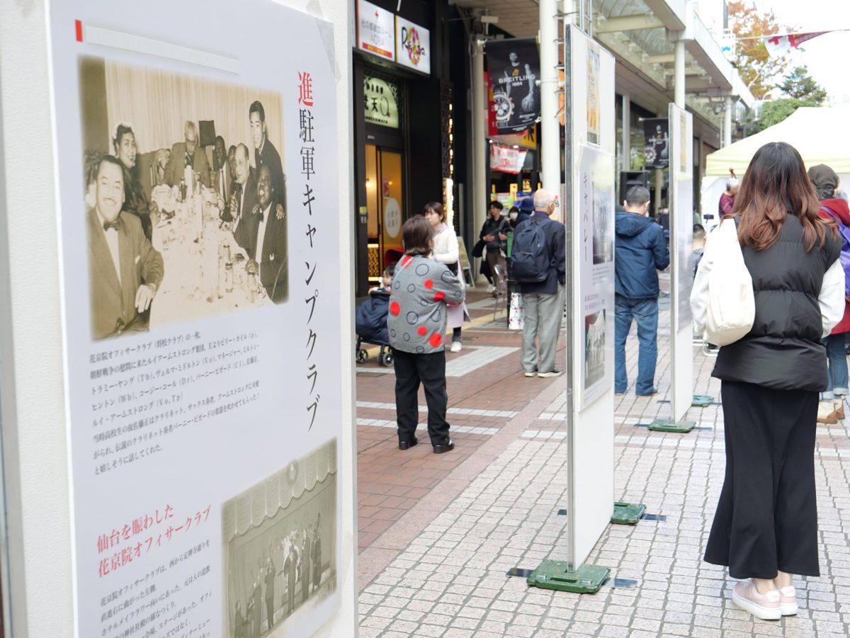 商店街に立てたパネル展示。進駐軍キャンプクラブの写真と解説を通行人が見ている